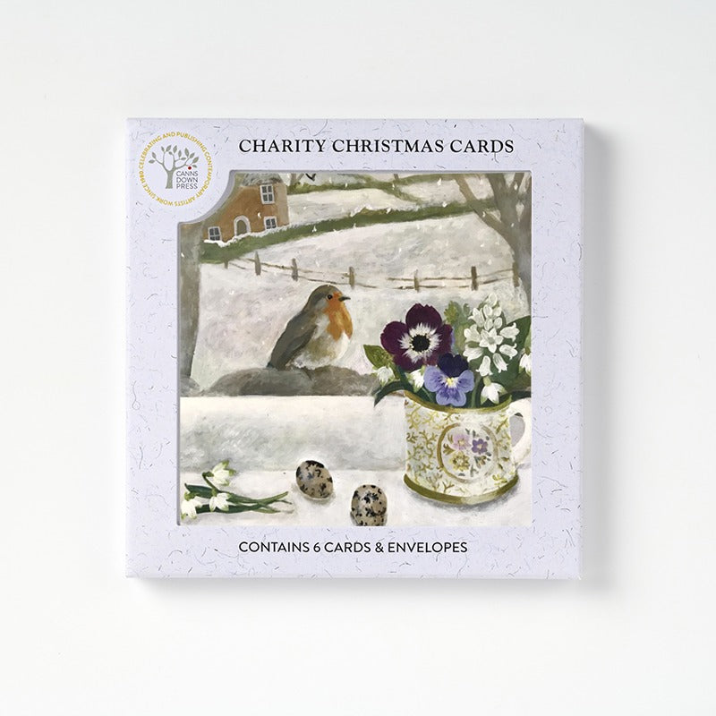 A boxed set of 6 Christmas cards featuring a robin visitor on a snowy branch out side a window with a vase of flowers.