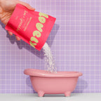 A fun picture of someone pouring the Birthday Cake bath salts into a toy pink bath.
