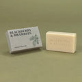 A bar of natural soap next to its textured gray packaging box, both embossed and printed with the brand name 'Blackberry & Brambles' on a muted olive green background.