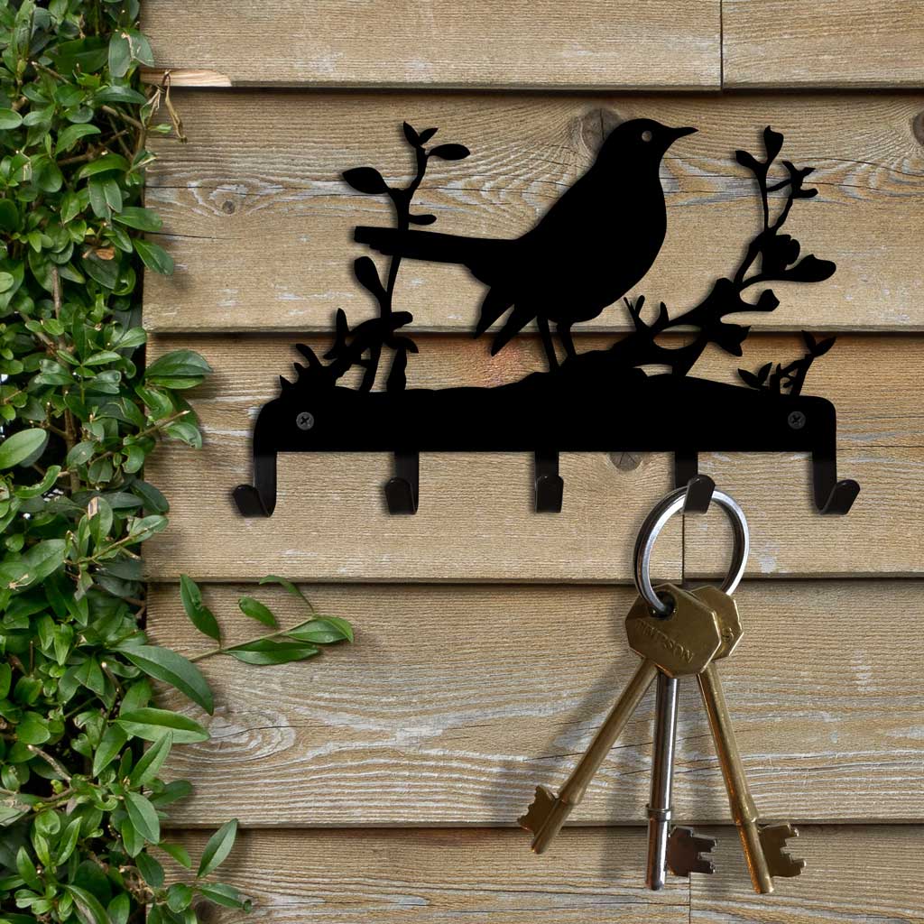 Decorative key holder with bird design on wooden wall