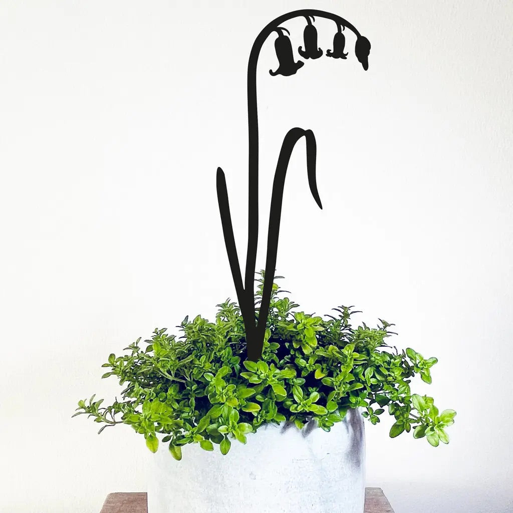 Decorative metal pot stem in shape of bluebells with green plant on a white background