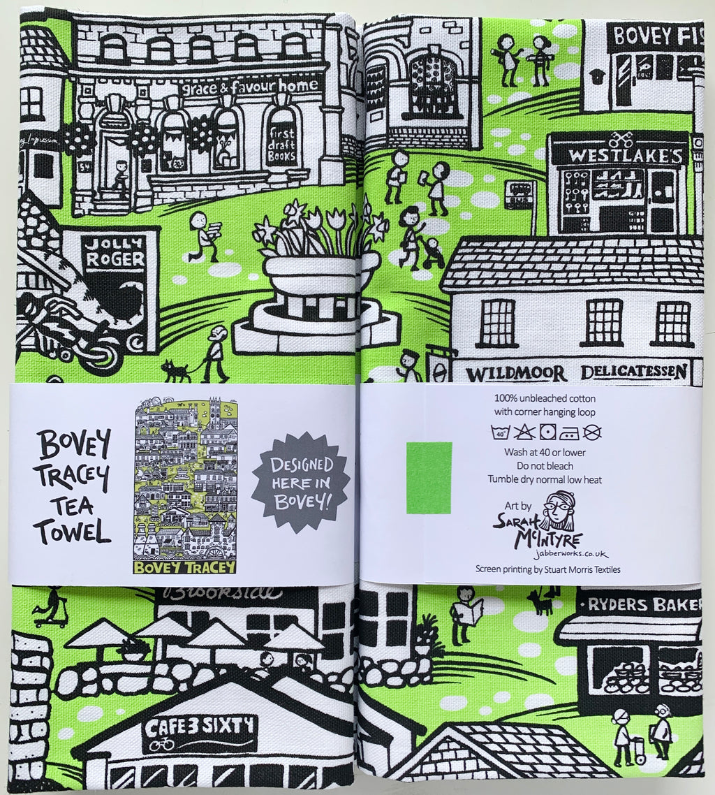 Tea towel with black and white illustrations of Bovey Tracey town on a green background