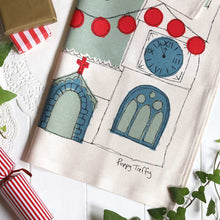 Decorative tea towel with artistic designs of a clock, church door, and window, featuring the brand 'Poppy Treffry'.