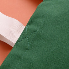 Close-up of dark green 'Jolly tired' tote bag fabric with white straps.