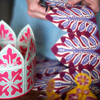 Person cutting out a colourful paper crown with intricate patterns by Cambridge Imprint