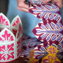 Person cutting out a colourful paper crown with intricate patterns by Cambridge Imprint
