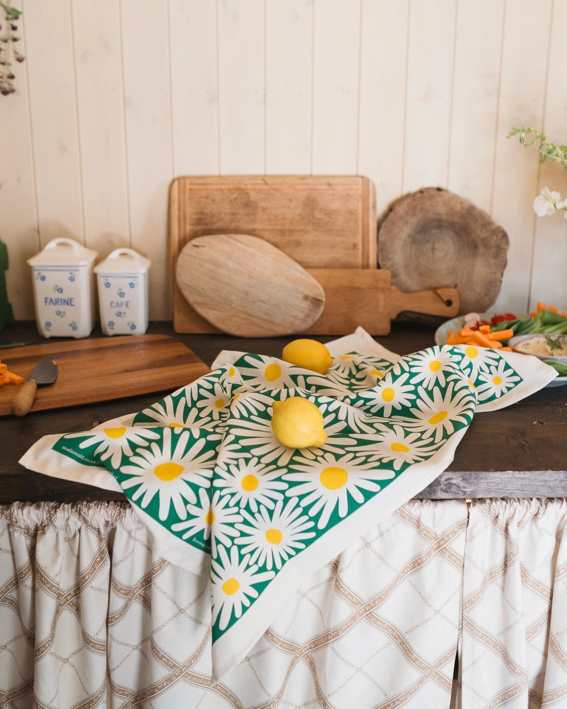 Daisy-patterned towel on a kitchen worktop with lemons and kitchen items.