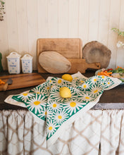 Daisy-patterned towel on a kitchen worktop with lemons and kitchen items.
