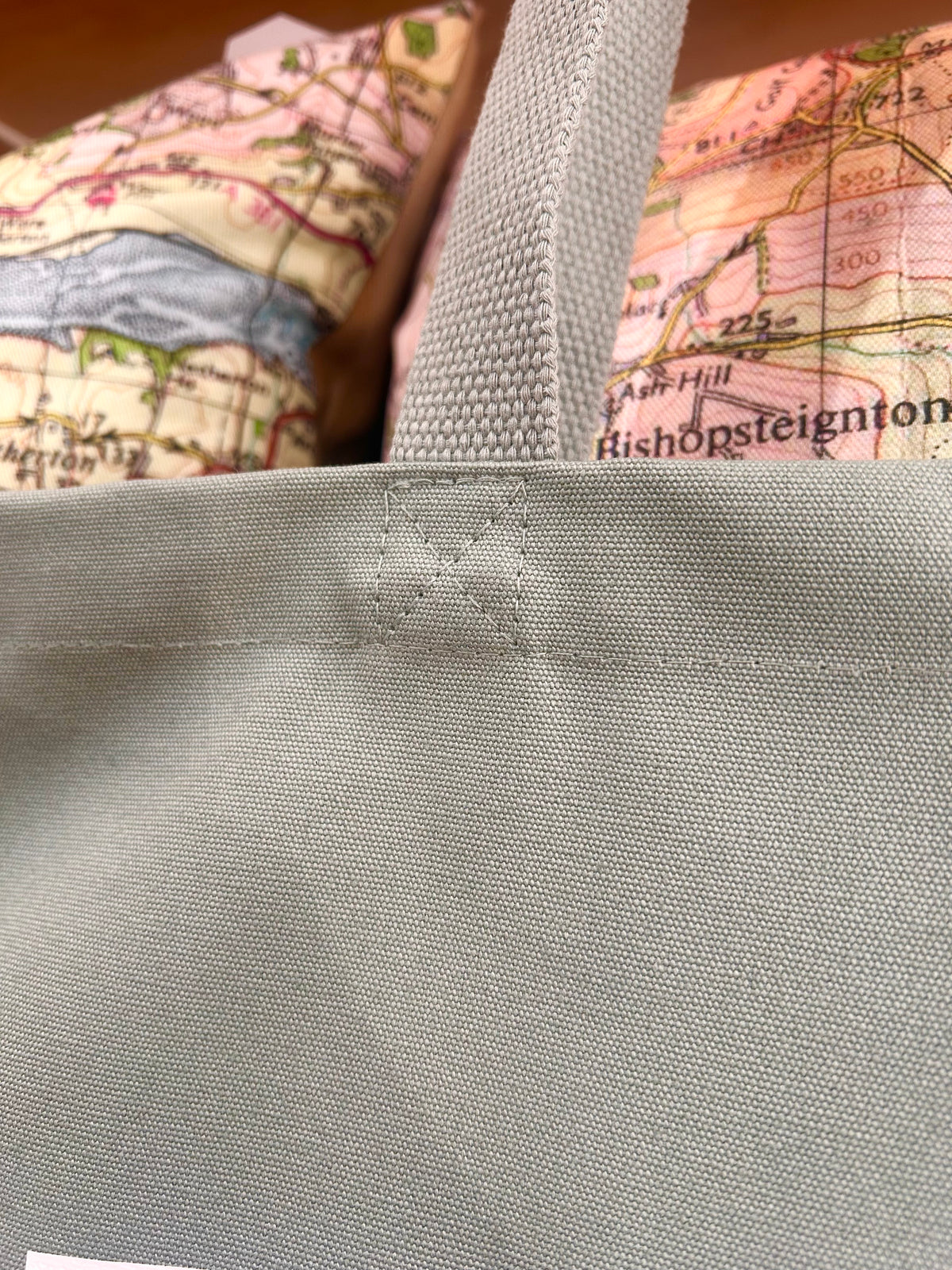 Sage green tote bag with a map design in the background