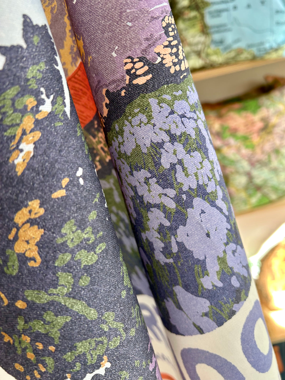 Close-up of Emsworthy Mire tea towel showing a botanical landscape print with purple flowers, green foliage.