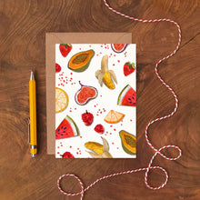 Greeting card with fruit pattern on a wooden surface with a pen and string.