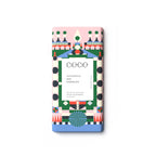 A single rectangular chocolate bar wrapped in a colorful geometric paper sleeve, centered on a plain white background. The wrapper features a pink top section, a blue bottom section, and a central white panel with black text reading 'COCO GINGERBREAD MILK CHOCOLATE'.