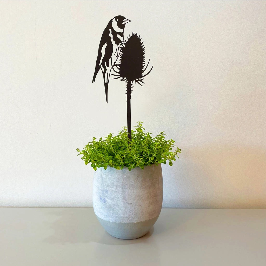 Black metal pot stem inserted in a plant pot featuring a goldfinch on a teasel.