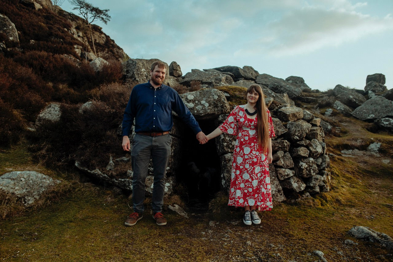 A photo of Grace & Favour Home founders, Rachael and Steve, standing in front of rocks on Dartmoor