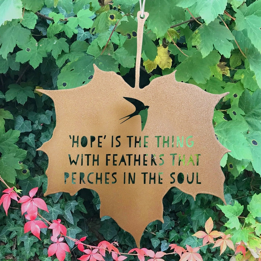 Leaf-shaped sign with motivational quote on a green leafy background
