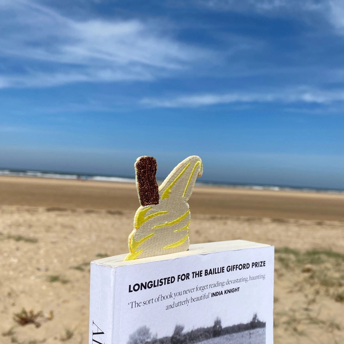 Ice cream cone embroidered bookmark tucked inside a book at the seaside