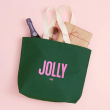 Green tote bag with 'JOLLY tired' text on a pink background