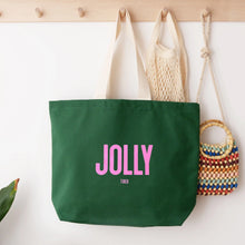 Green tote bag with 'Jolly Tired' text, hanging against a wall