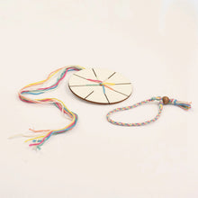 Colourful friendship bracelet-making kit with a wooden disc and threads on a light background