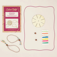 Cotton Twist friendship bracelet making kit with packaging, wooden wheel, colorful strings, and a completed bracelet on a beige background.