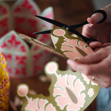 Person cutting out the paper crowns with scissors by Cambridge Imprint