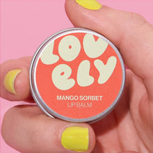 Lip balm, Mango Sorbet flavoured, held by a hand with yellow nail polish on a pink background.