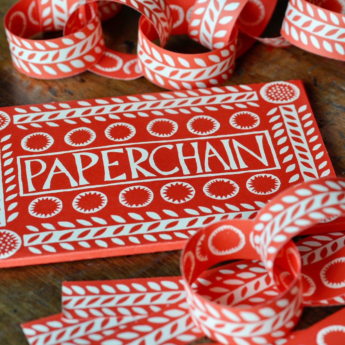 Red and white paper chain with 'Paperchain' packaging on a wooden surface