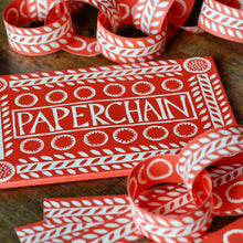 Red and white paper chain with 'Paperchain' packaging on a wooden surface