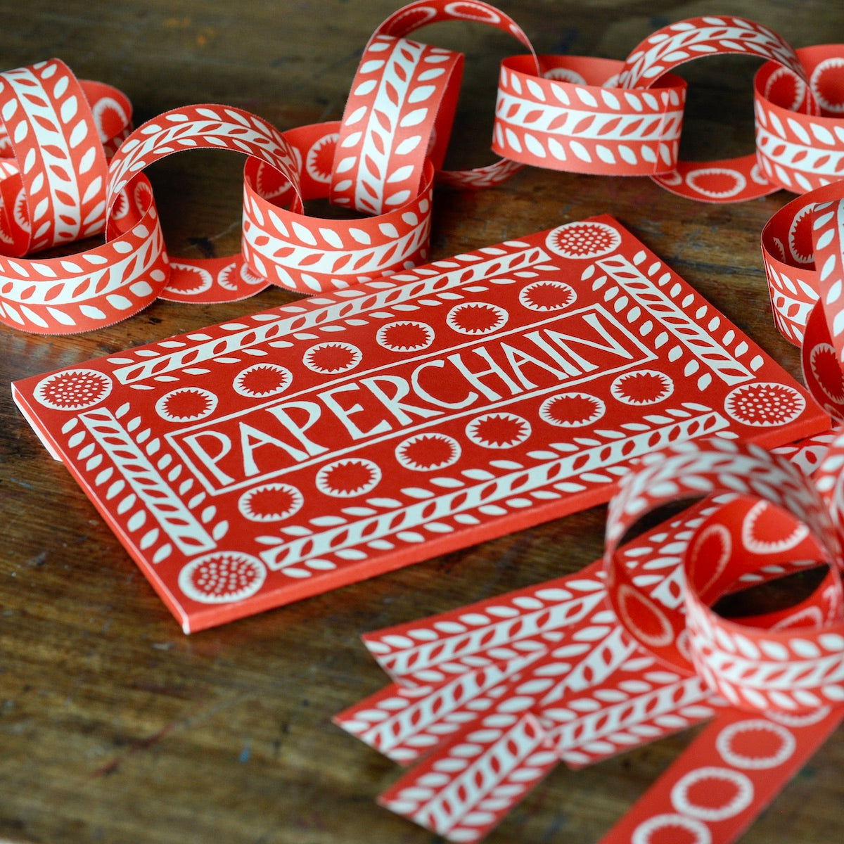 Red and white paper chain with packaging on a wooden surface