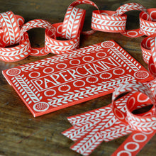 Red and white paper chain with packaging on a wooden surface