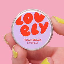 Lip balm tin with being held with the wording 'Lovely' and 'Peach Melba lip balm'.