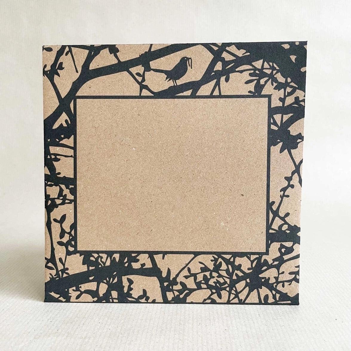 Printed kraft envelope front with black cut-out branches and birds on a white background