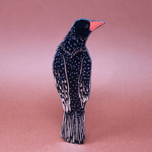 Black leather rook shaped bookmark with silver foil details against a pink background. 