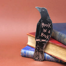 Reverse of decorative bookmark shaped like a crow with 'Rook in a Book' text on top of books.