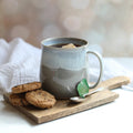 Gray mug with tea and cookies on a wooden board