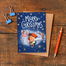 Christmas card with cartoon characters on a wooden surface with a pen and clips.