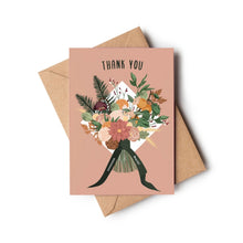 A thank you card with a dusty pink background and an illustrated bouquet of flowers tied with a dark green ribbon, shown with a brown kraft envelope on a white background.