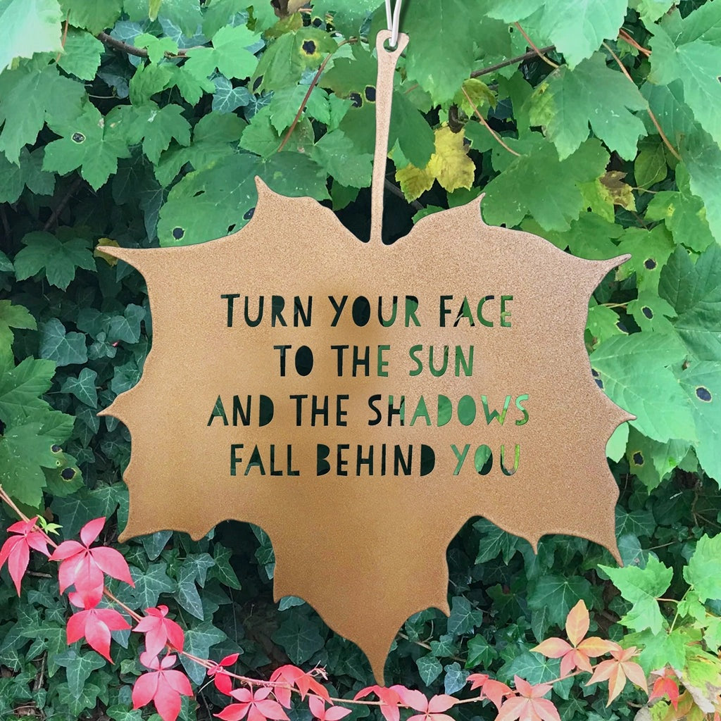 Leaf-shaped sign with motivational quote on a green leafy background