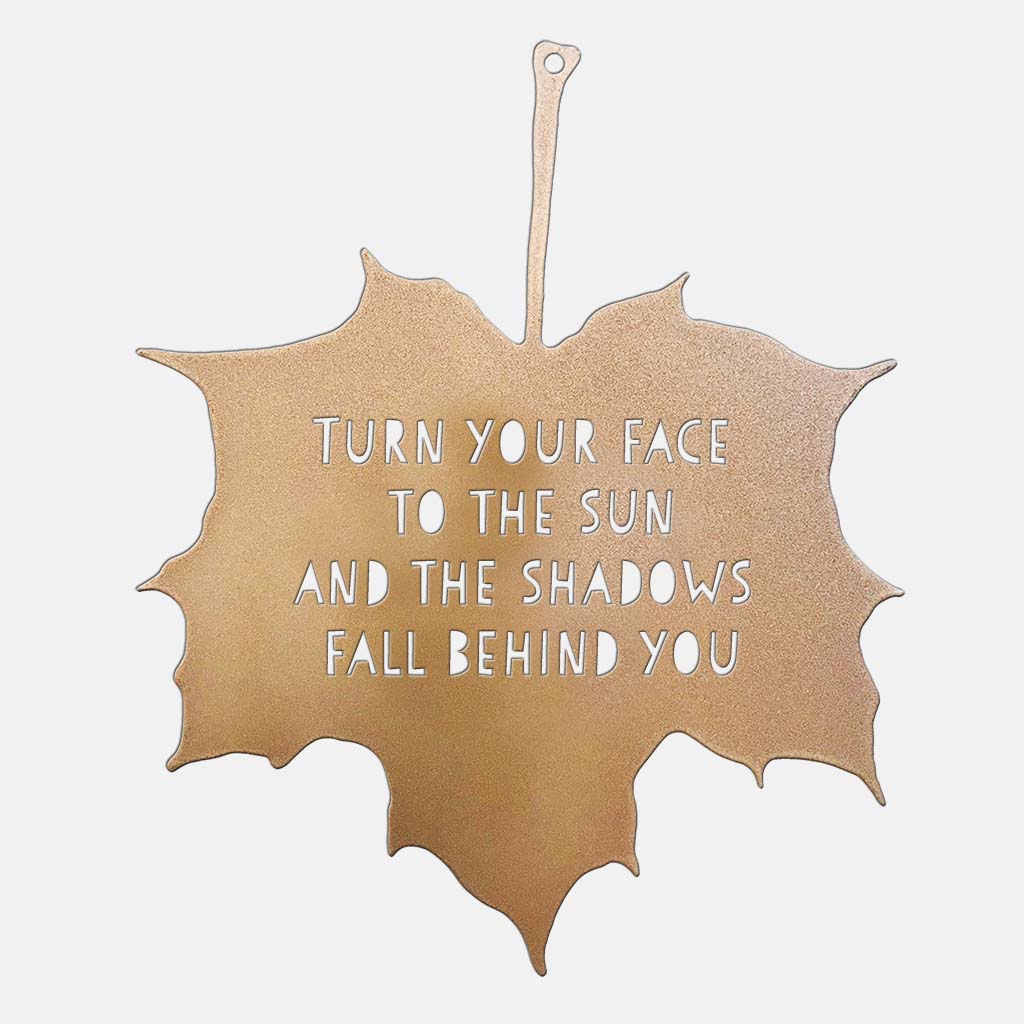 Gold leaf-shaped sign with motivational quote on a white background