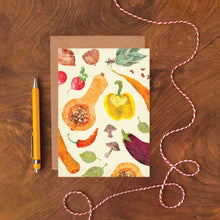 Card with vegetable pattern on a wooden surface with a pen and string.