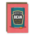 Card with a can of beans illustration and humorous text on a red background