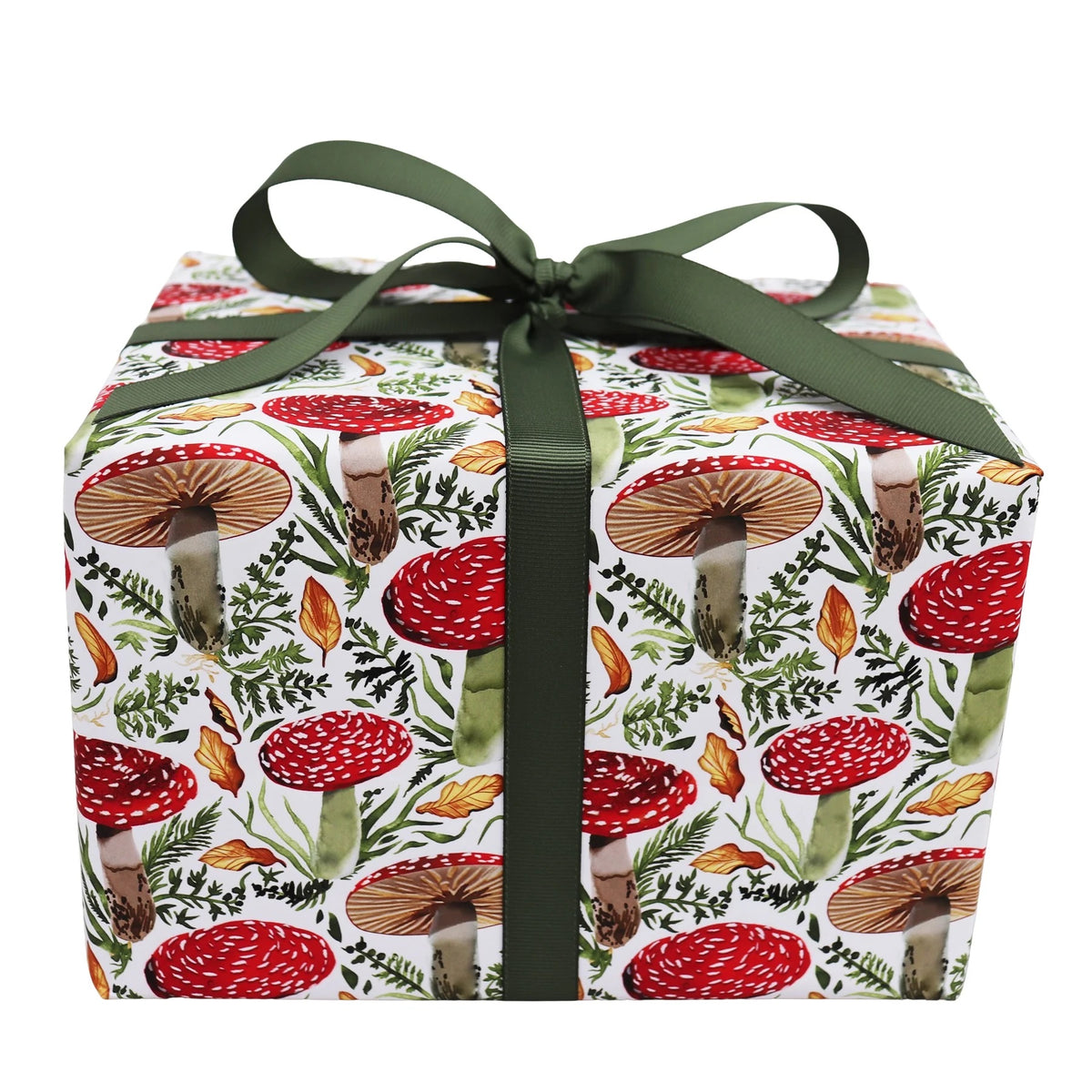 A square gift box wrapped in white paper with a red and green mushroom and leaf pattern, tied with a dark green ribbon bow, on a white background.