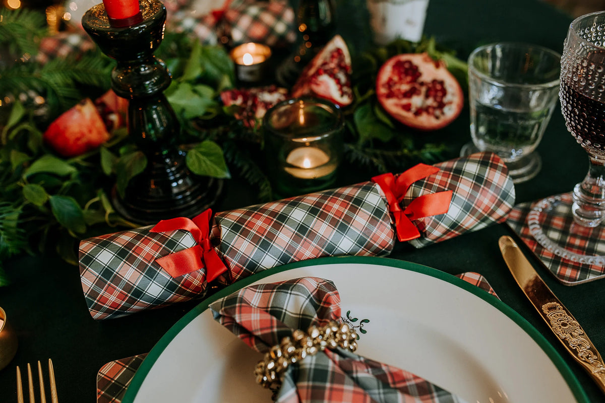 Placesetting with tartan crackers and green foliage.